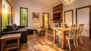 Een moderne woonkamer met een bank, een salontafel, een eettafel met stoelen, een open haard en een televisie waarop 'NETFLIX' wordt weergegeven.