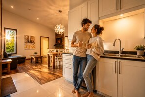 A modern kitchen with white cabinets, a stainless steel sink, and a dining area with wooden furniture.