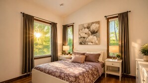 Une chambre à coucher avec un lit, des tables de chevet, une commode, un tableau et des rideaux.