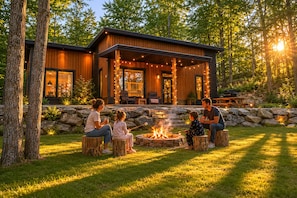 Una casa moderna con una chimenea exterior, asientos al aire libre y un muro de piedra.