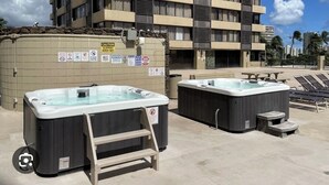 Een hotel met twee buitendouches, een stenen muur met waarschuwingsborden en een meerlaags gebouw op de achtergrond.