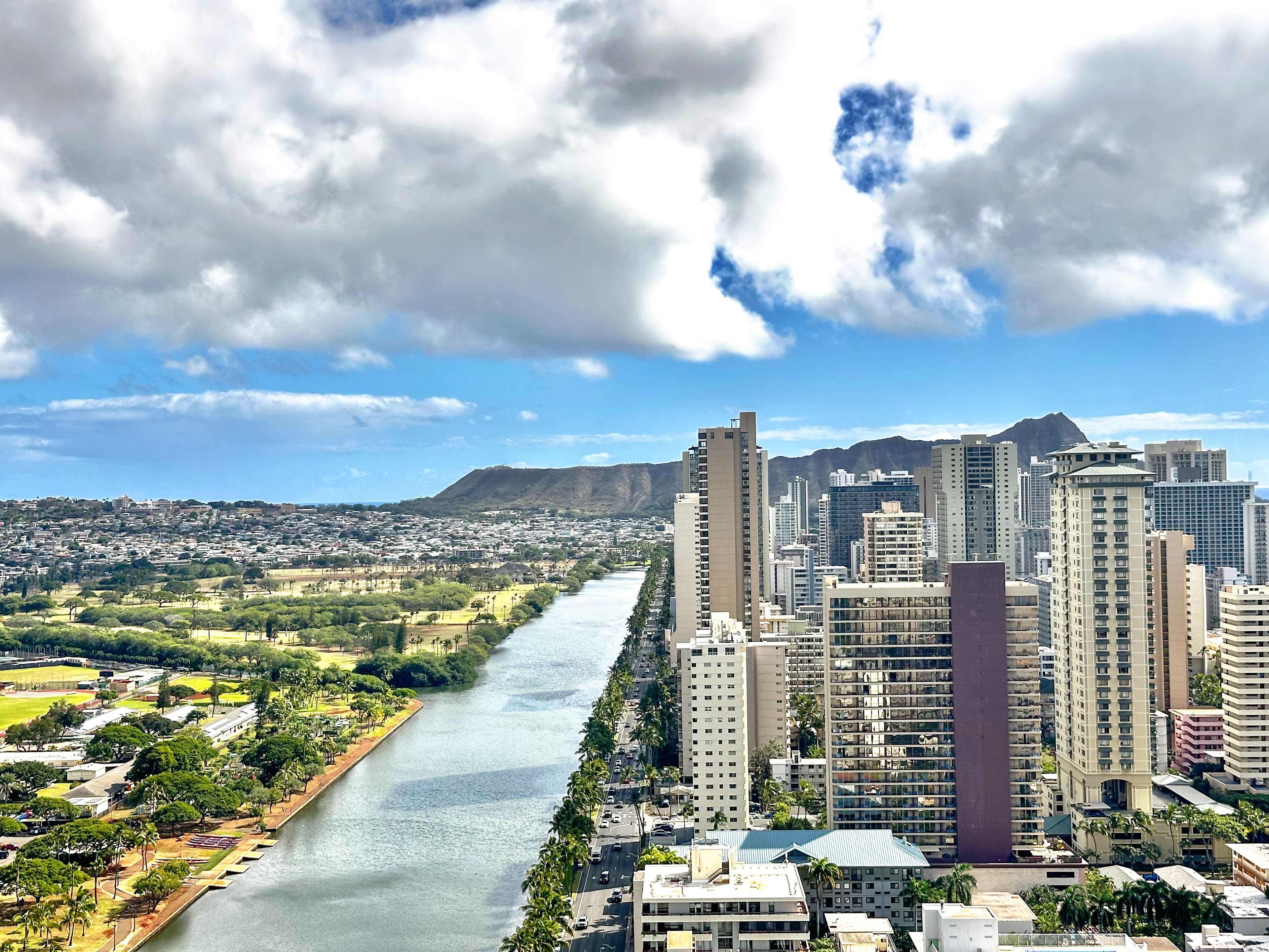A cityscape with a river running through it, surrounded by high-rise buildings and a mountain in the background.