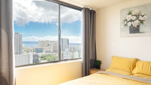 Een kamer met een bed, een raam met uitzicht op de stad, een schilderij aan de muur en een gordijn.