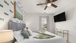 A bedroom with a bed, a ceiling fan, a TV on the wall, and a window with curtains. - City-Close Durham Stay Near Downtown~Self Check-In~King Suite~Free Parking (Durham)
