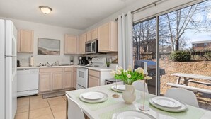 A modern kitchen with light wooden cabinets, a stainless steel microwave, and a dining area with a table set for four. - City-Close Durham Stay Near Downtown~Self Check-In~King Suite~Free Parking (Durham)