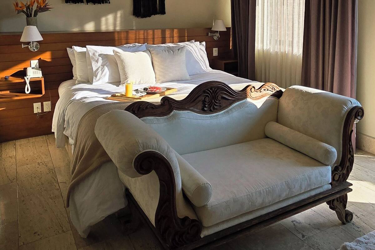 A spacious bedroom with a large bed, wooden headboard, and a nightstand with a lamp.
