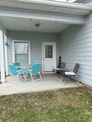 A covered porch with a table and chairs, a door, and a small window. - Beach Days, Nightlife Nights, East End of PCB (Panama City)