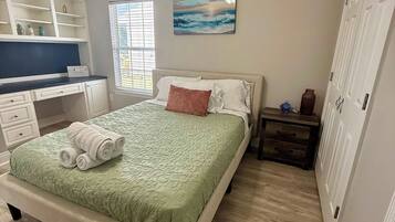 A bedroom with a bed, a desk, a chair, a nightstand, and a wardrobe.