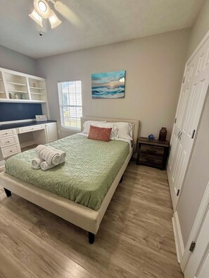 A bedroom with a bed, a desk, a chair, a nightstand, and a wardrobe. - Beach Days, Nightlife Nights, East End of PCB (Panama City)