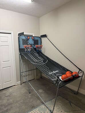 Ein kleiner Basketballplatz in Innenräumen mit Netz, zwei Basketballkörben und einigen Basketballsäcken.