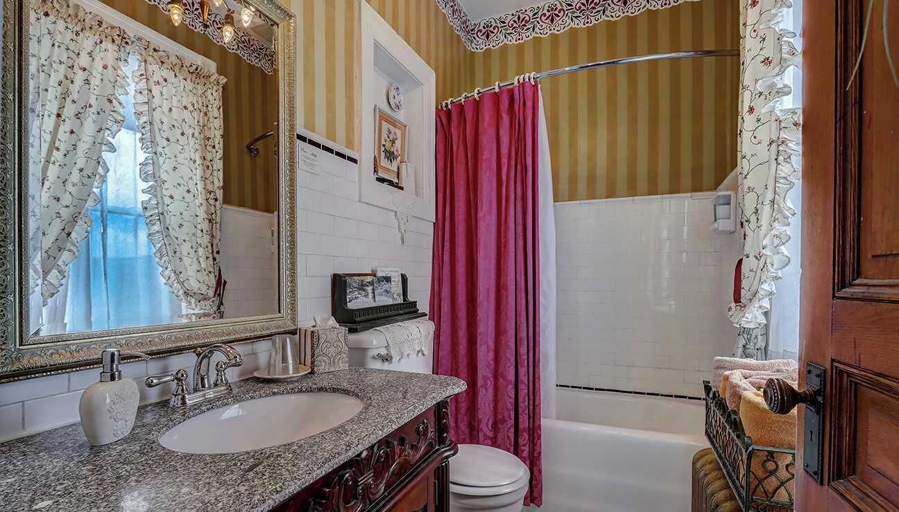 A bathroom with a double sink, a mirror, a bathtub, and a shower curtain.
