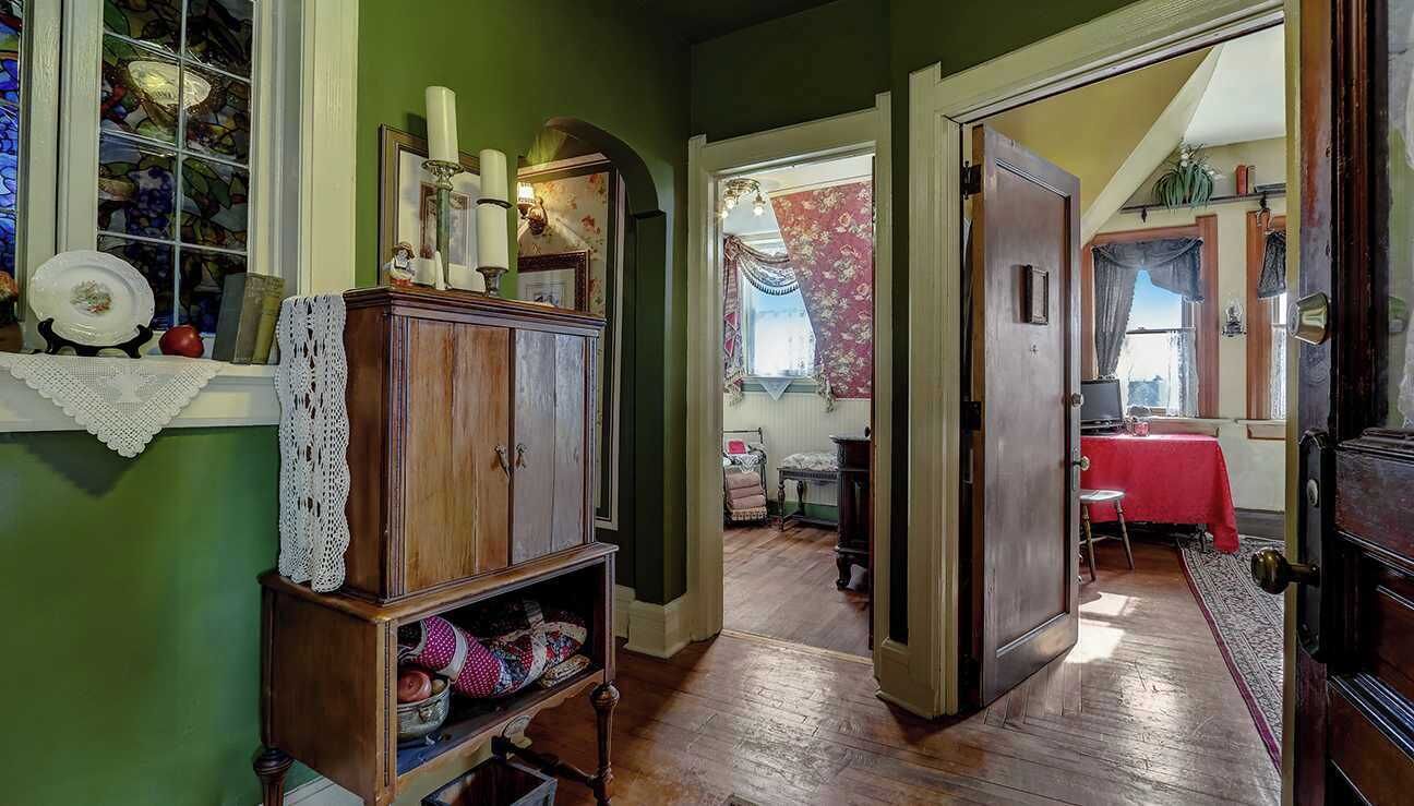 A room with a wooden cabinet, a lace doily, and a stained glass window.
