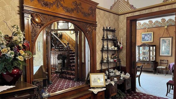 Ein prachtvoller Raum mit einem großen Spiegel, einer Treppe und einer Holzkommode mit Dekorationen.