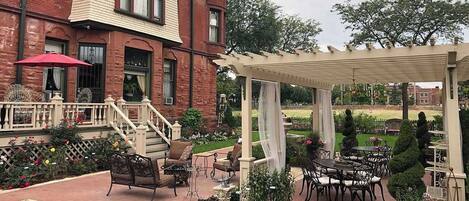 Un patio con mobiliario exterior, una pérgola y un edificio de ladrillo al fondo.