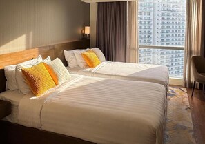 A hotel room with two beds, a view of a cityscape, and a large window with curtains. - Eleve Suites (Mandaluyong)