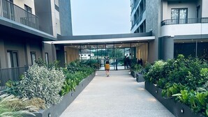 Ein modernes Gebäude mit einem zentralen Fußweg, der von Grünflächen und Glasüren zum Innenbereich gesäumt wird.