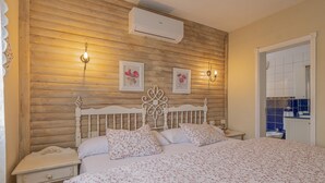 Ein Schlafzimmer mit Holzwand, einem weißen Bett mit floralem Bettzeug, zwei Nachttischlampen und einem kleinen Nachttisch.