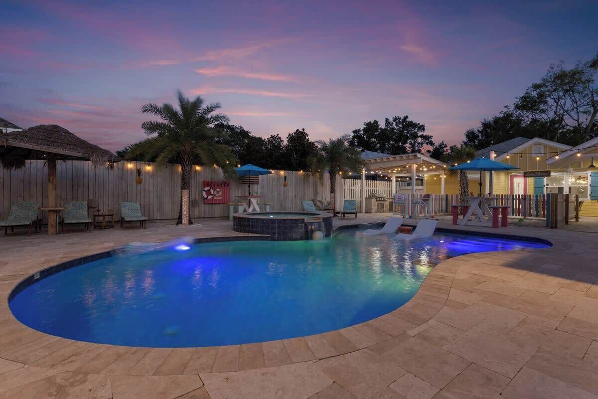 Piscina con hidromasaje, rodeada de vallas de madera y sillas de descanso.