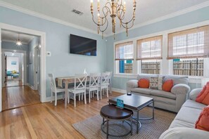 A living room with a sofa, coffee table, and dining area with chairs. - The Anchor Once Upon A Tide Villas! POOL! (Bay St. Louis)