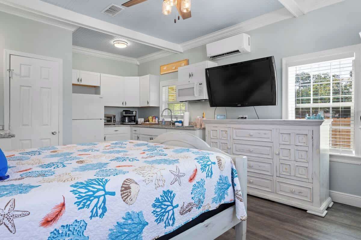 A bedroom with a bed, a TV, a dresser, and a window.