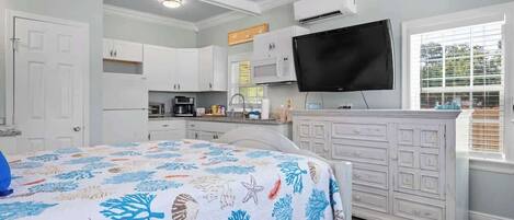 A bedroom with a bed, a TV, a dresser, and a window.