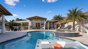 A swimming pool with lounge chairs and a hot tub, surrounded by palm trees and a covered patio area. - Honeymoon Suite with Shared POOL! (Bay St. Louis)