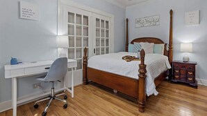 A bedroom with a wooden four-poster bed, a desk with a chair, and a dresser. - Honeymoon Suite with Shared POOL! (Bay St. Louis)