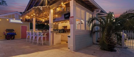 Un restaurant doté d’une terrasse, d’un toit de chaume et de guirlandes lumineuses.