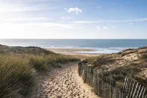 A sandy beach path leading to the ocean with a wooden fence on one side. - Marais Bleu - Apartment 50 meters from the beach (Saint-Hilaire-de-Riez)