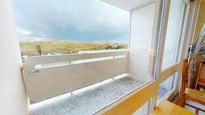 Ein Balkon mit Blick auf eine grüne Landschaft und einen bewölkten Himmel.