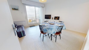 Un coin repas avec une table ronde, des chaises et un téléviseur fixé au mur.