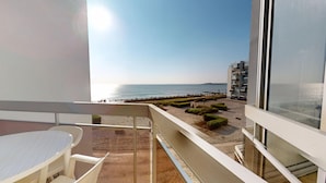 Un balcon avec vue sur la mer, une table et des chaises.