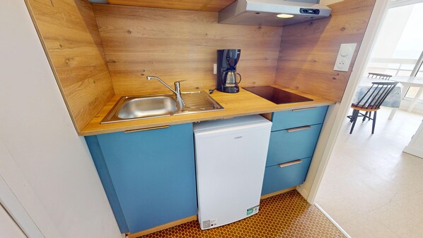 A compact kitchenette with a sink, coffee maker, and a mini-fridge.