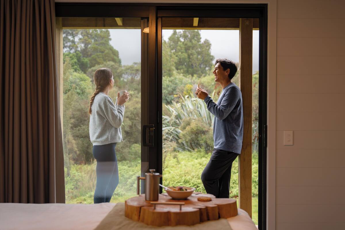 Ein Zimmer mit einer großen Schiebetür, die in einen Garten führt. Im Inneren steht ein Holztisch mit einer Schüssel und einer Tasse.