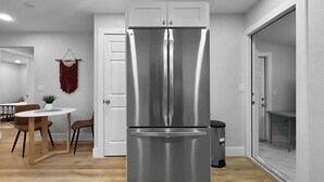 A modern kitchen with a stainless steel refrigerator, wooden dining table, and chairs. - Casa De Campo Unit B Up to 3 (Tampa)
