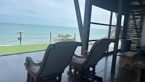 Une pièce avec deux fauteuils à bascule placés devant une grande fenêtre donnant sur la mer.