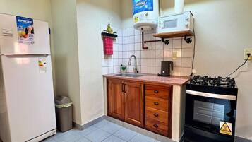 Cocina compacta con refrigerador, dispensador de agua, microondas, fregadero y estufa.