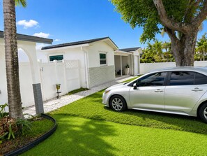 A residential property with a white exterior, a driveway, and a parked car. - Tropical Haven Dania (Dania Beach)