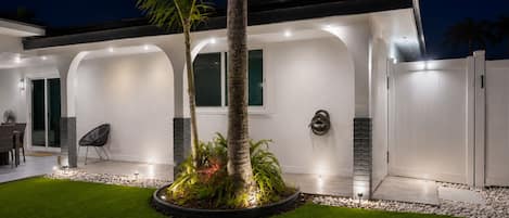 A modern house with a covered patio, a dining area, and a well-maintained lawn.