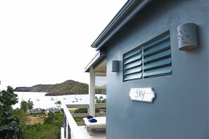 A balcony with a view of a body of water, a sign reading 'Sky', and a building with a blue exterior. - SKY.   Beach Beach Beach Wake up to ocean views. Walk to the beach in 3 minutes! (St Pauls)
