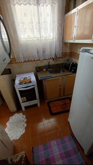 Uma cozinha compacta com geladeira, pia e fogão pequeno.