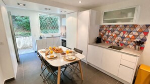 A modern kitchen with white cabinetry, a dining table set for breakfast, and a colorful backsplash.