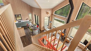 Un intérieur moderne avec un escalier en bois, un coin repas et une cheminée.