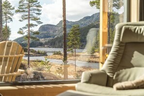 A room with a view of a river and mountains. There is a chair and a couch. - Nyborg Hytte 8p - Four Bedroom Chalet, Sleeps 8 (Vrådal)