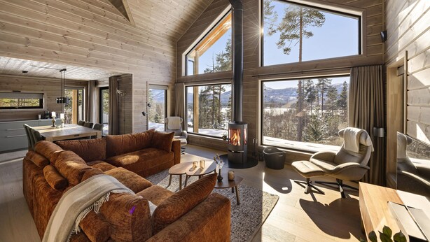 A spacious living area with a large fireplace, wooden furniture, and large windows offering a mountain view. - Lothlórien Lodge 8p - Four Bedroom Chalet, Sleeps 8 (Vrådal)