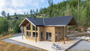 A wooden cabin with large windows and a deck, surrounded by forest. - Lothlórien Lodge 8p - Four Bedroom Chalet, Sleeps 8 (Vrådal)