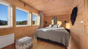 A wooden cabin bedroom with a bed, a radiator, a window, and a view of the outdoors. - Verhøf Hytte 9p - Four Bedroom Chalet, Sleeps 9 (Vrådal)