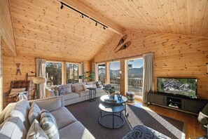 L’intérieur d’un chalet en bois chaleureux et accueillant, avec un canapé, une table basse et un téléviseur.