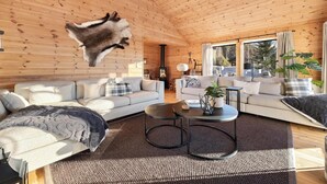 A spacious living room with a high wooden ceiling, two sofas, a coffee table, and a large window. - Verhøf Hytte 9p - Four Bedroom Chalet, Sleeps 9 (Vrådal)