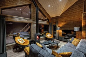 Un salon chaleureux avec une cheminée, des sièges confortables et de grandes fenêtres.